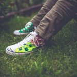 Teenager with jeans and colorful shoes on grass