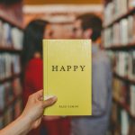 Hand holding yellow book with "Happy" written on the cover