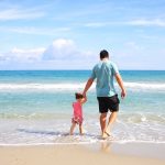 man and child walking along the beach