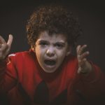 child in red outfit expressing anger