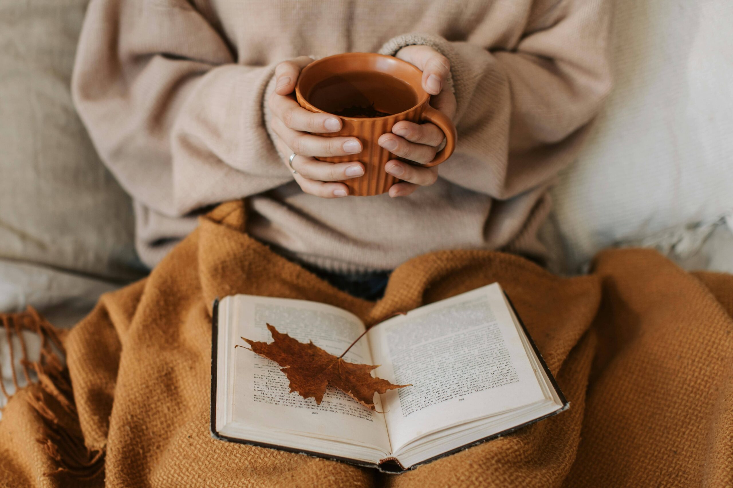 Relaxed woman with tea and book in her lap reflecting prevention of emotional exhaustion in Nashville tn