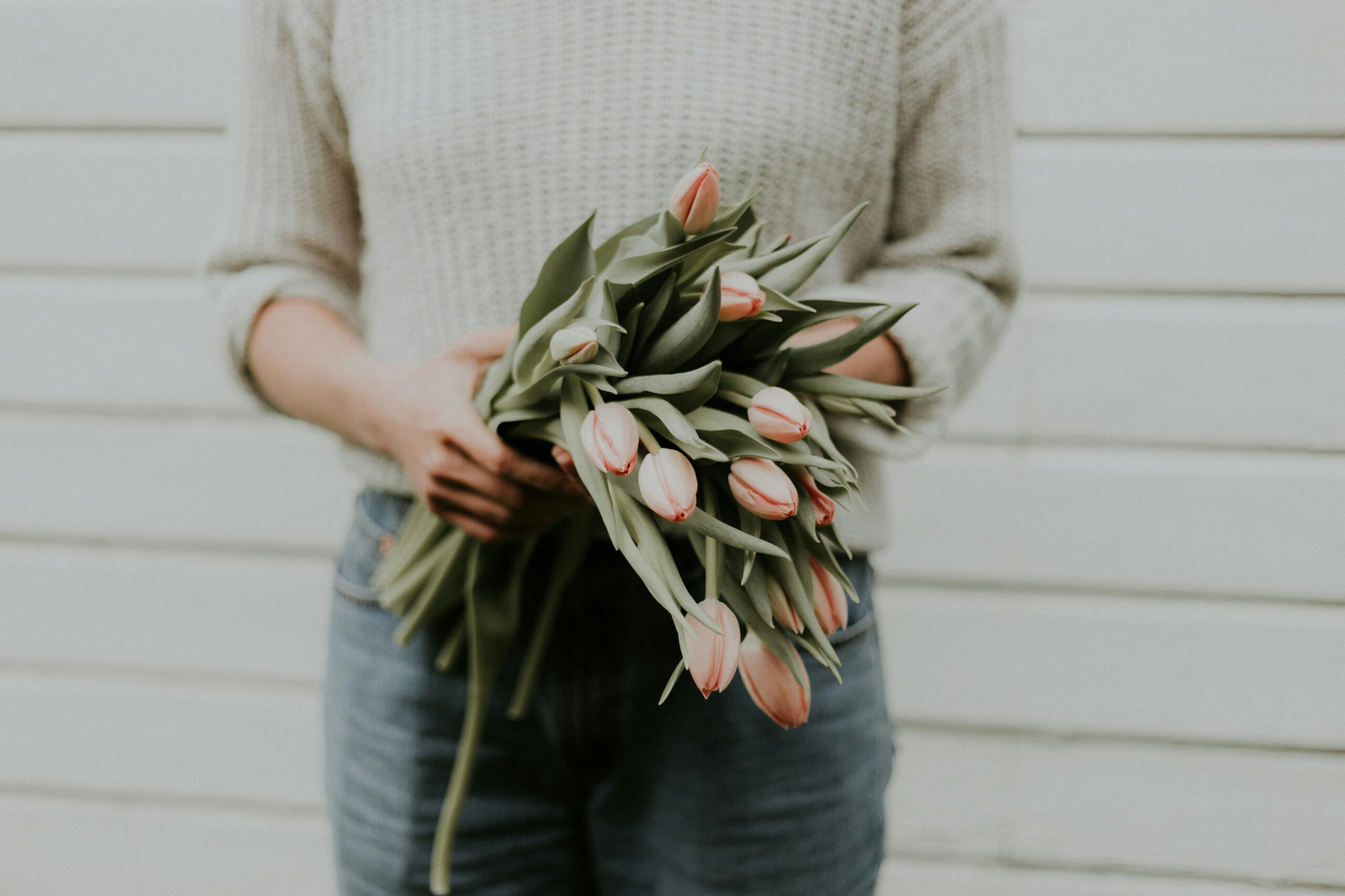 Person holding a fresh bouquet of pink tulips, conveying softness, care, and recovery from people pleasing