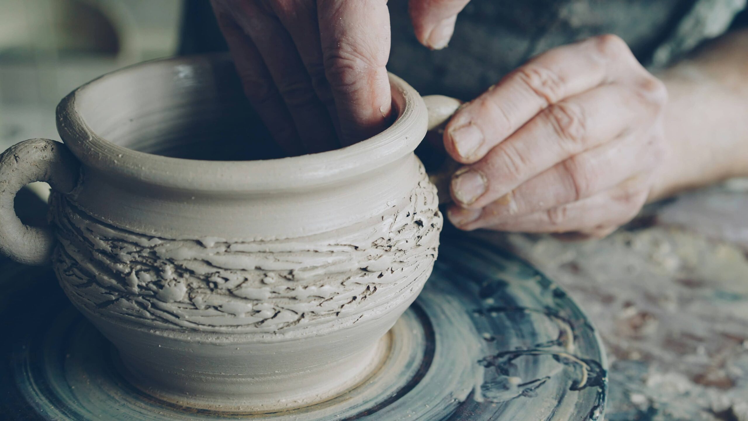Person finishes sculpting a mug on pottery wheel