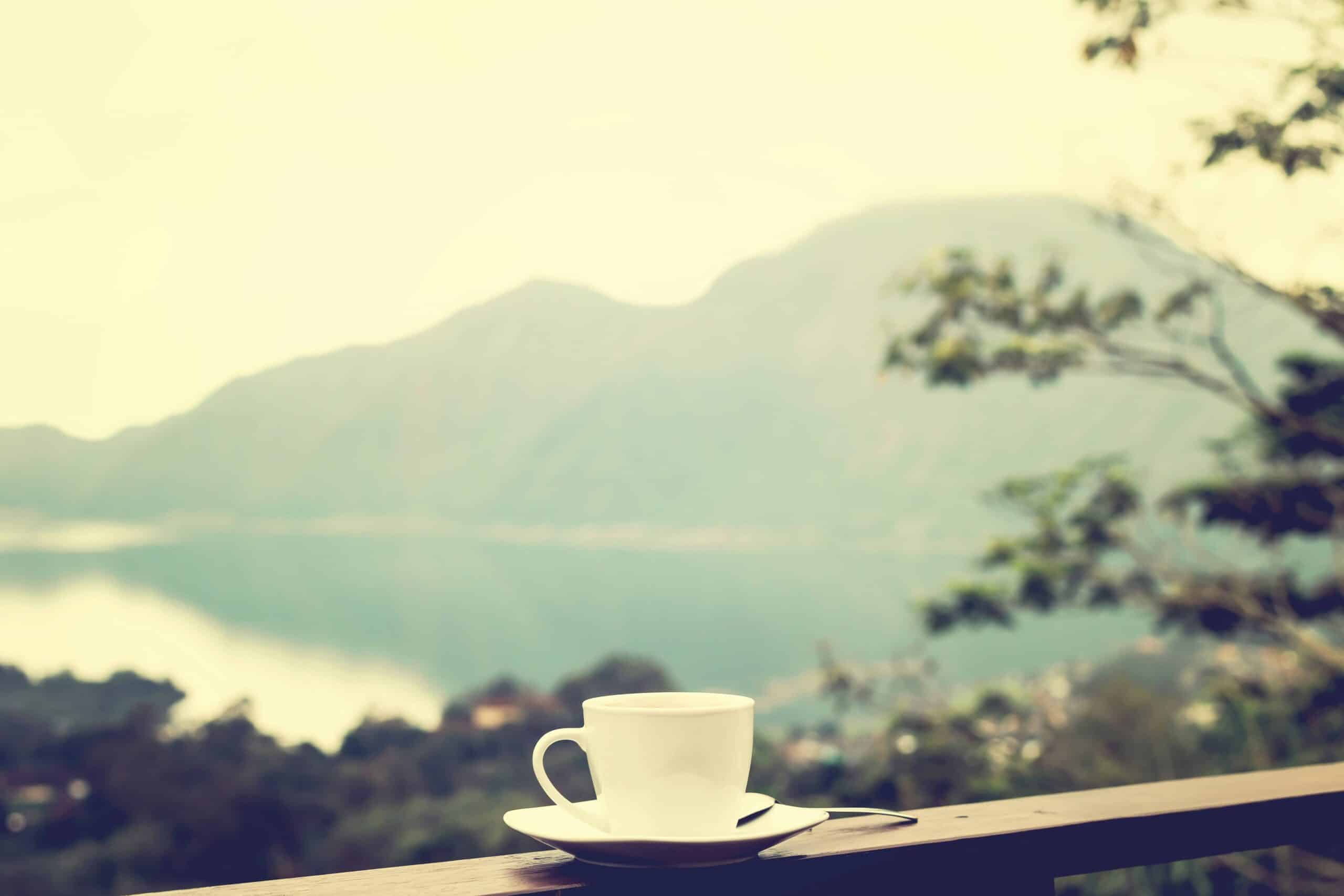 Beautiful mug and saucer on balcony overlooking image of mountains and lake to reflect internal peace and calm created by therapy for lawyers